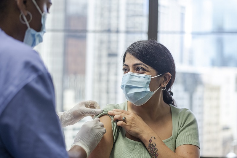 woman with mask getting vaccine from doctor