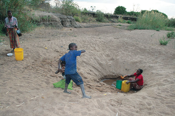 A family searching for water by digging deep into a dried riverbed during the dry season in northeastern Zambia.