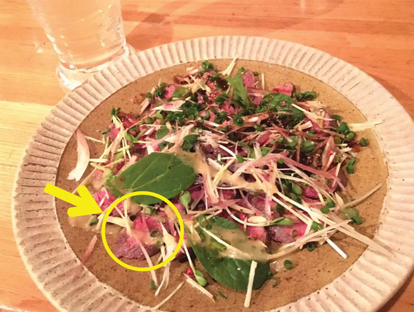 The bear meat dish implicated in an outbreak of Trichinella T9 infection, Japan, December 2016. Bear meat slices are marked with a circle and an arrow.