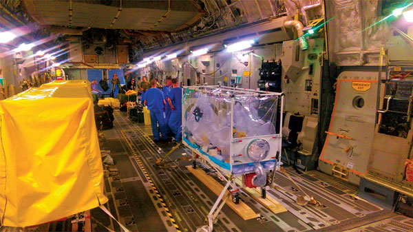 Multiple Air Transportable Isolator patient transport systems on a single aircraft (Boeing C-17 Globemaster). A single isolator is set up for the confirmed viral hemorrhagic fever case-patient; 2 additional isolators (left, covered) are available for the 2 exposed patients should they deteriorate or become symptomatic in flight.