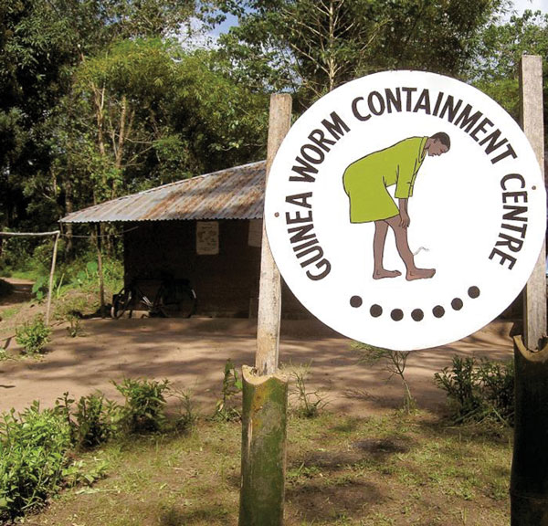 This 2004 photograph depicted the entrance to a Nigerian Guinea worm containment center. The sign at the entrance displayed a drawing of a Guinea worm sufferer. Photo by E. Staub, CDC/Carter Center. 