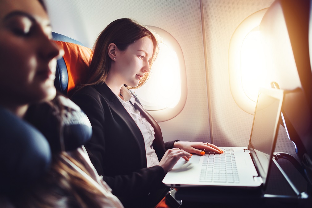 Business traveler working on laptop on airplane