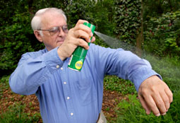 man spraying insect repellent