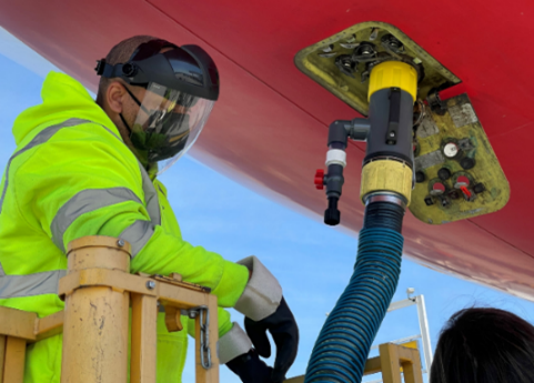 Worker collecting wastewater from an airplane